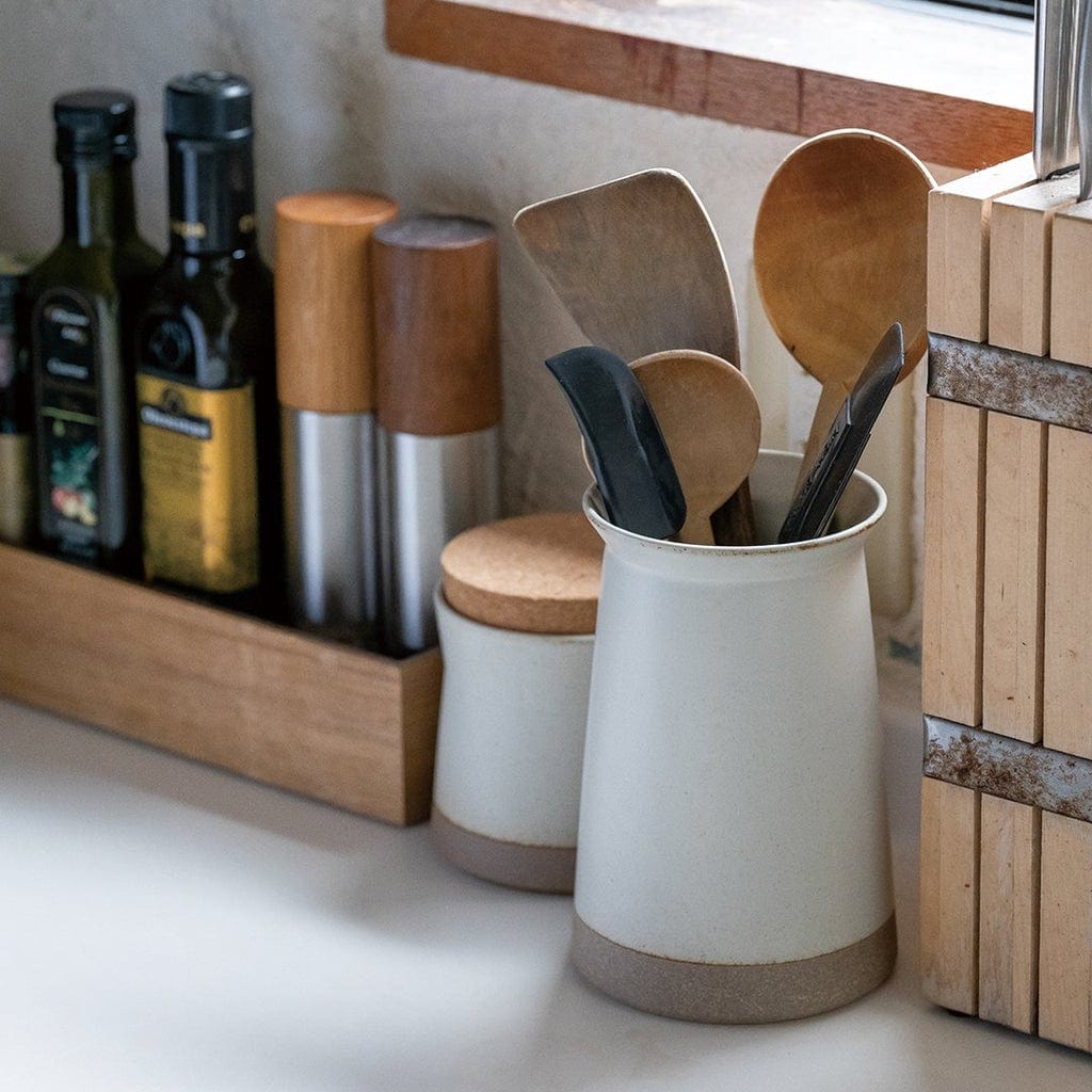 Kitchen counter with a ceramic holder containing wooden utensils, oils, and a knife block.