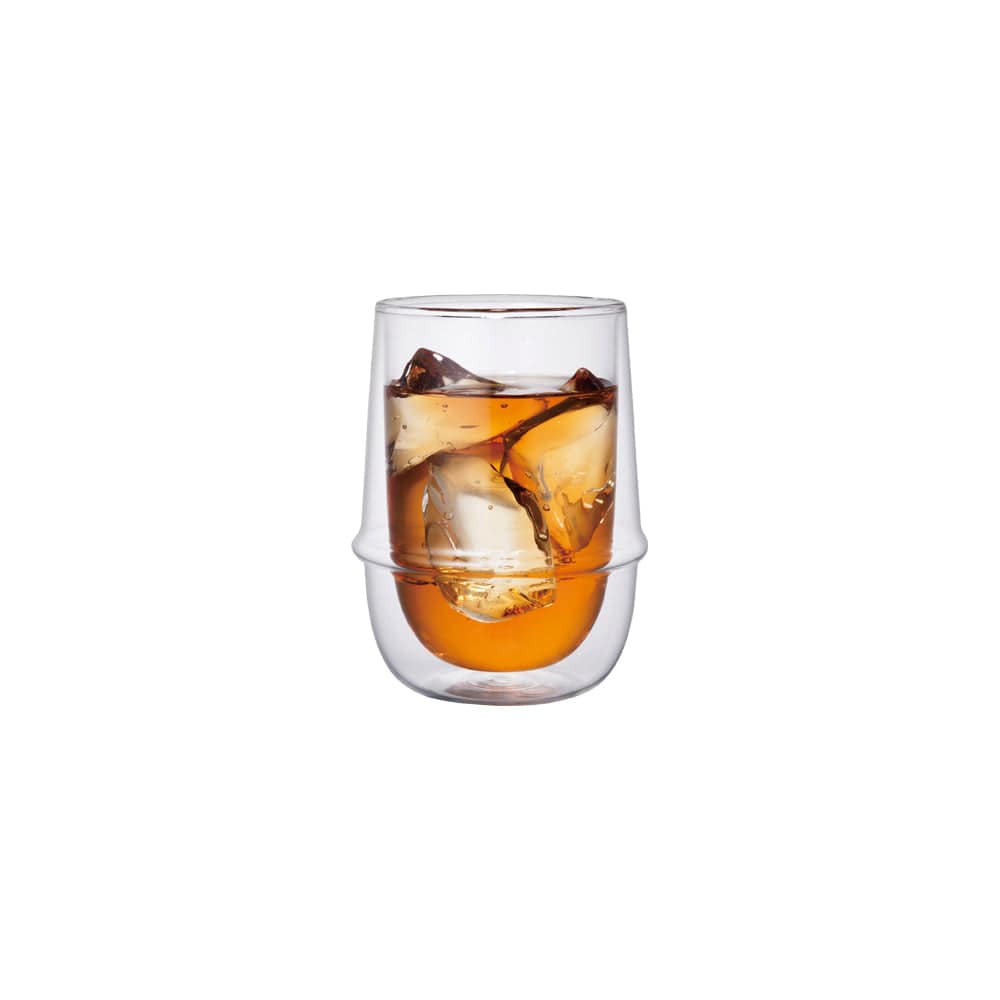 Tall glass with amber liquid and ice cubes inside, on a white background.
