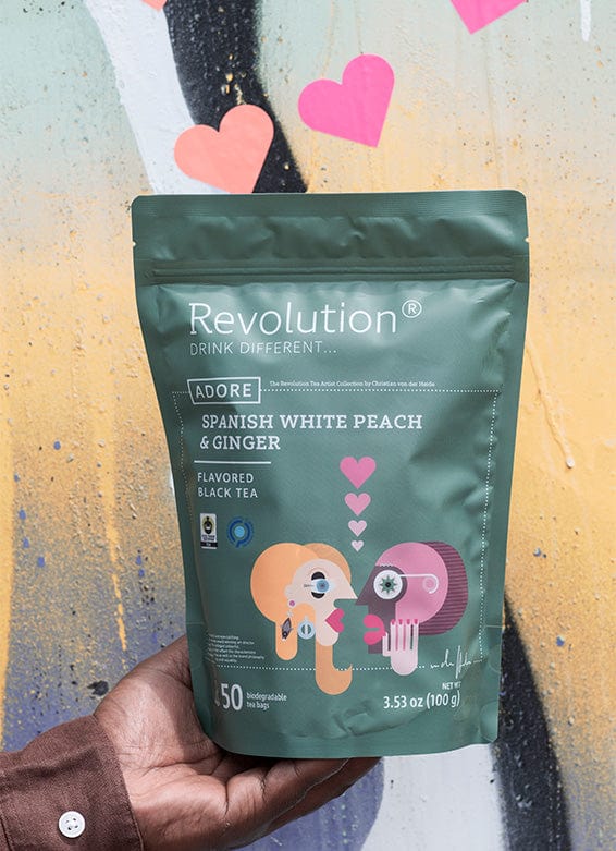 Hand holding a green bag of Revolution Spanish White Peach & Ginger tea.
