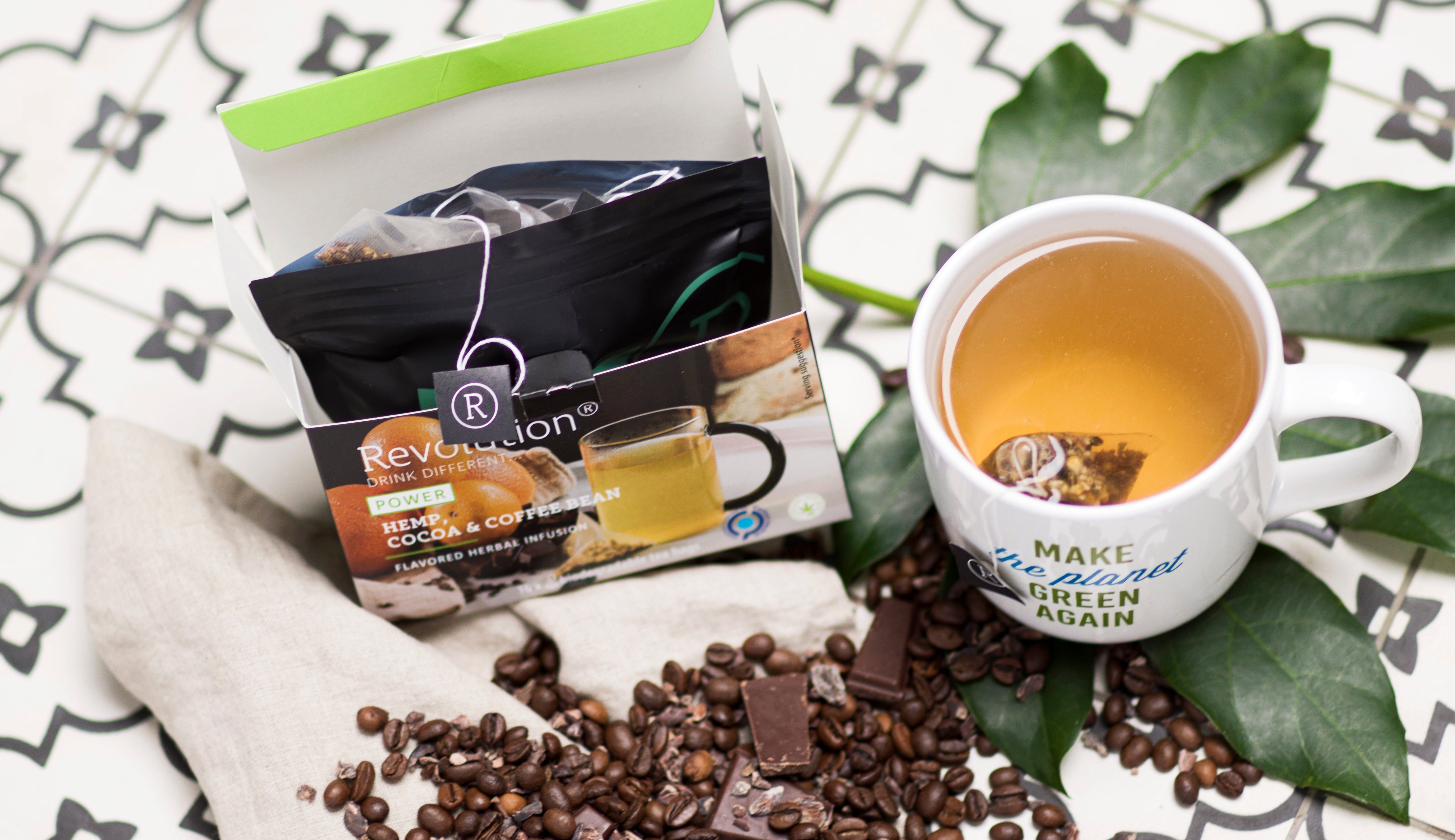 Tea box, mug with tea, coffee beans on a patterned surface.