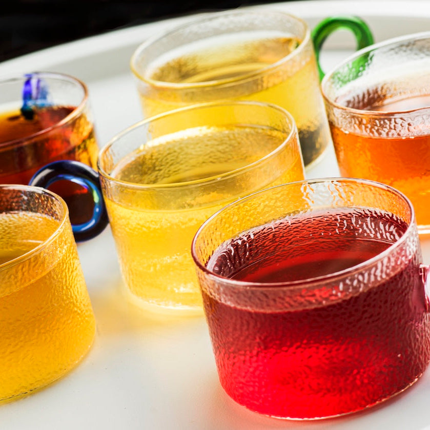 Assorted colored drinks in transparent cups on a white tray