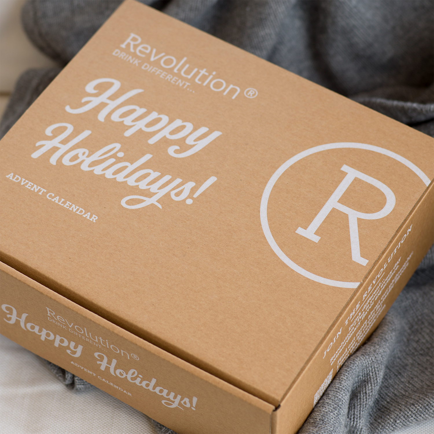 Closed brown box with text Revolution Merry Christmas Happy Holidays and large R logo.