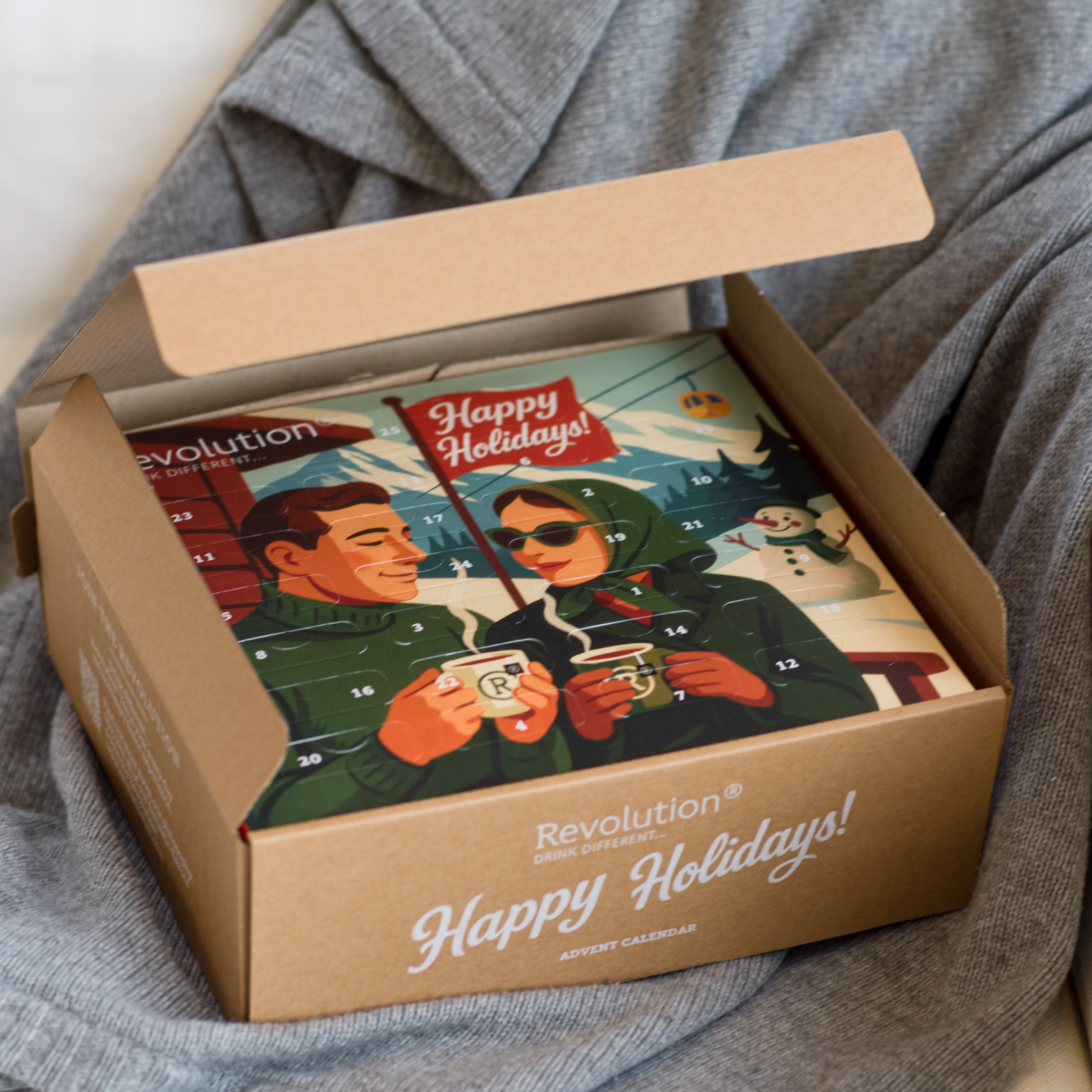 Open brown box revealing a Happy Holidays advent calendar with an illustrated couple.