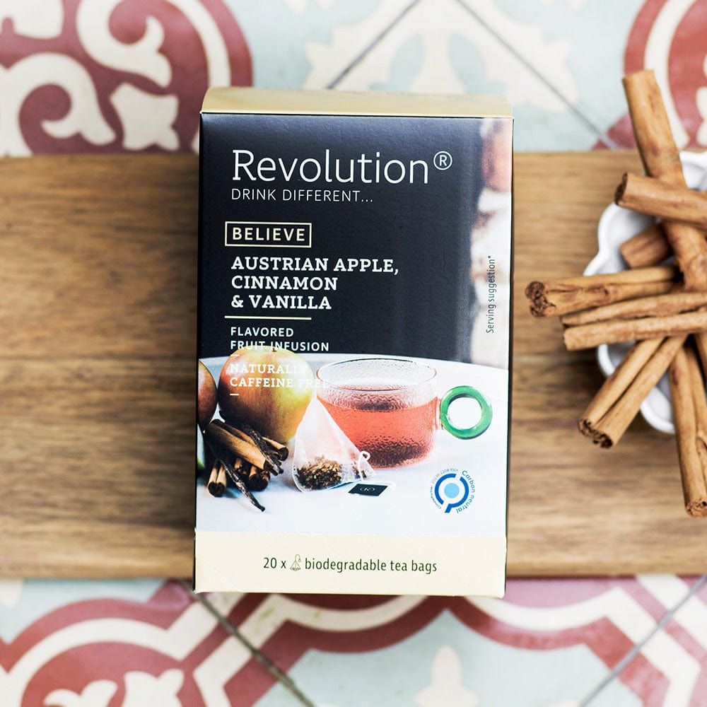 Box of Austrian Apple tea with cinnamon and vanilla surrounded by cinnamon sticks on patterned tile.