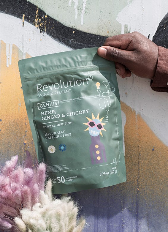 A hand holds a green tea pouch labeled 'Revolution' with hemp, ginger, and chicory against graffiti.