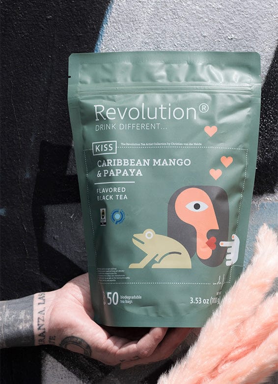 Hand holds a green pouch of Caribbean Mango & Papaya flavored black tea with abstract art.