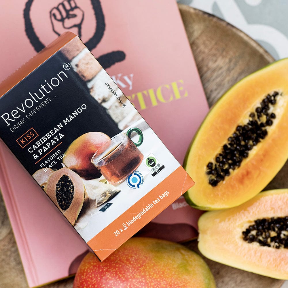 Caribbean Mango and Papaya tea box with sliced papaya on a wooden surface.