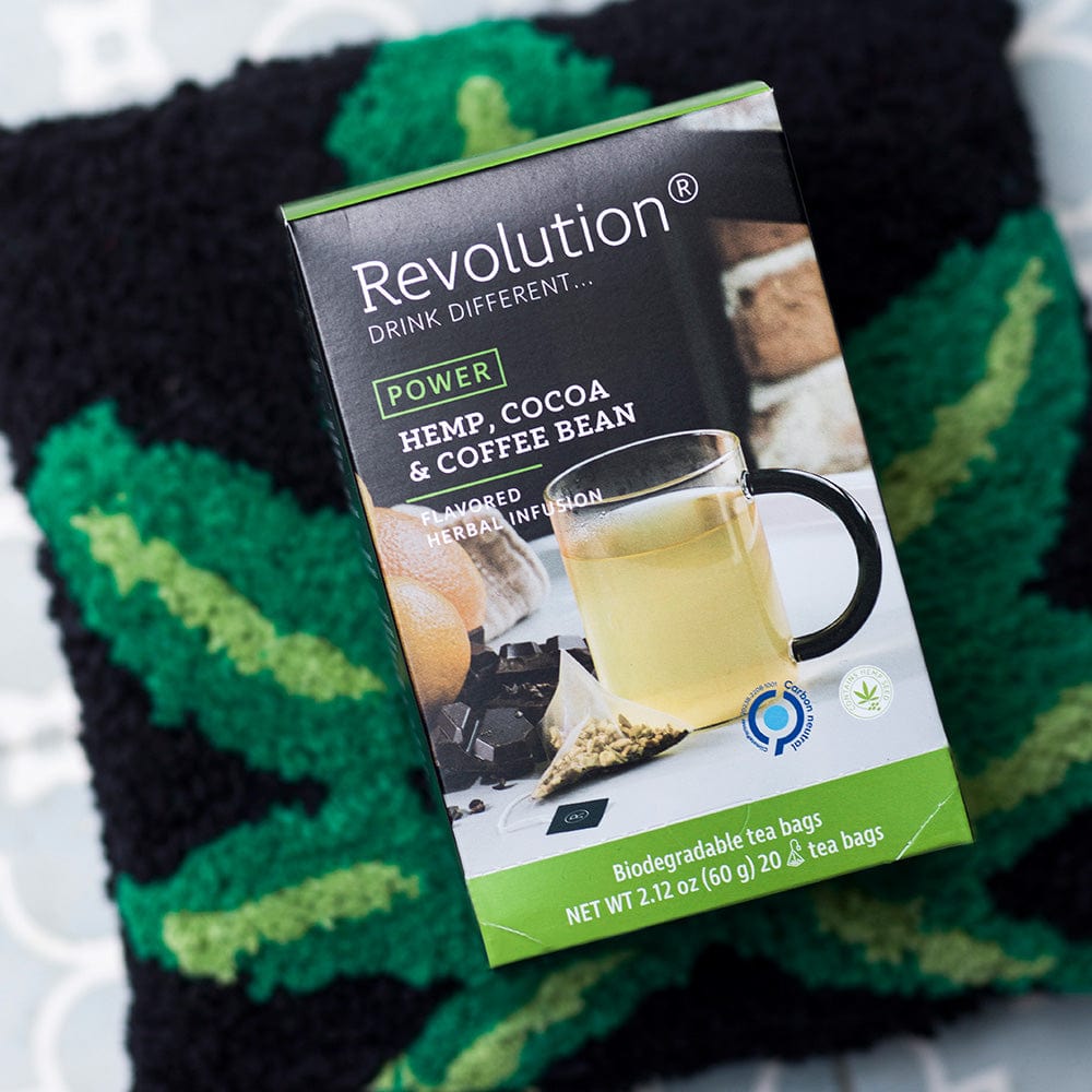 Revolution tea box labeled 'Power' with hemp, cocoa, and coffee bean flavors, on a patterned fabric.