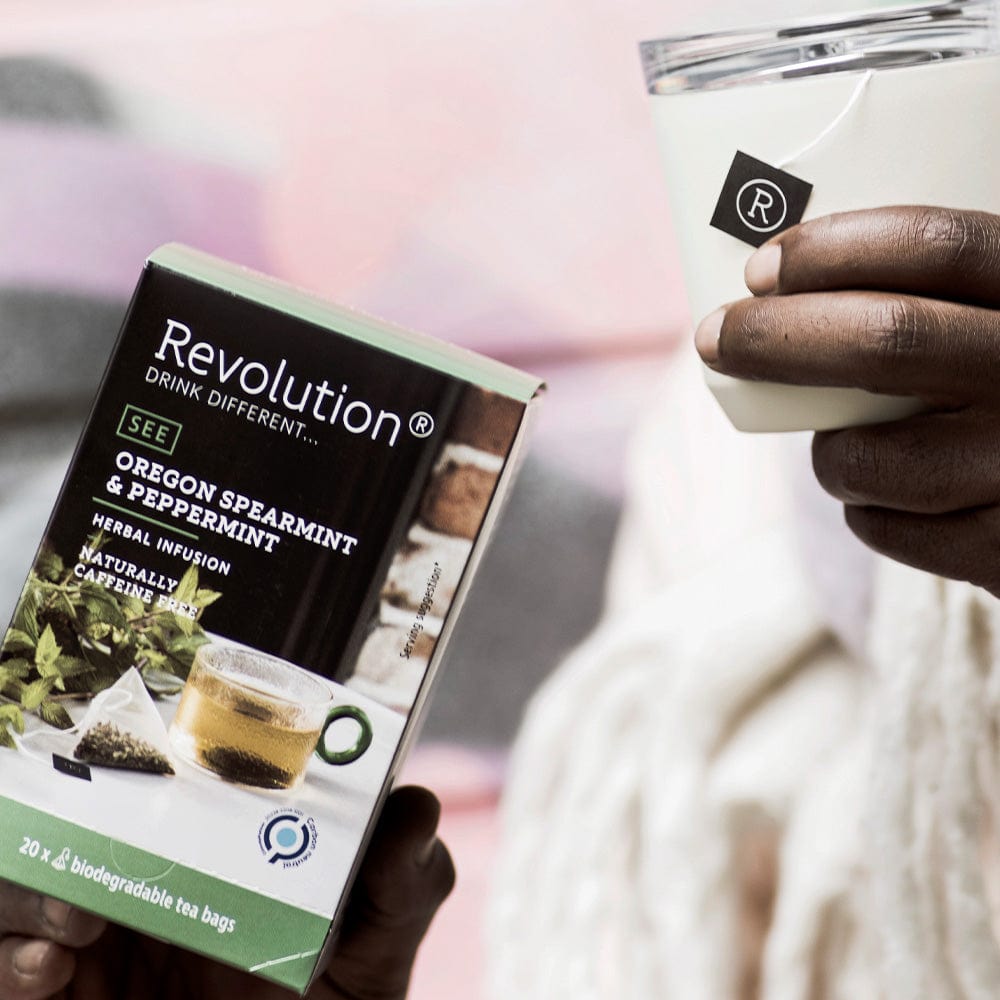 Person holding Oregon spearmint and peppermint infusion box and a white cup.