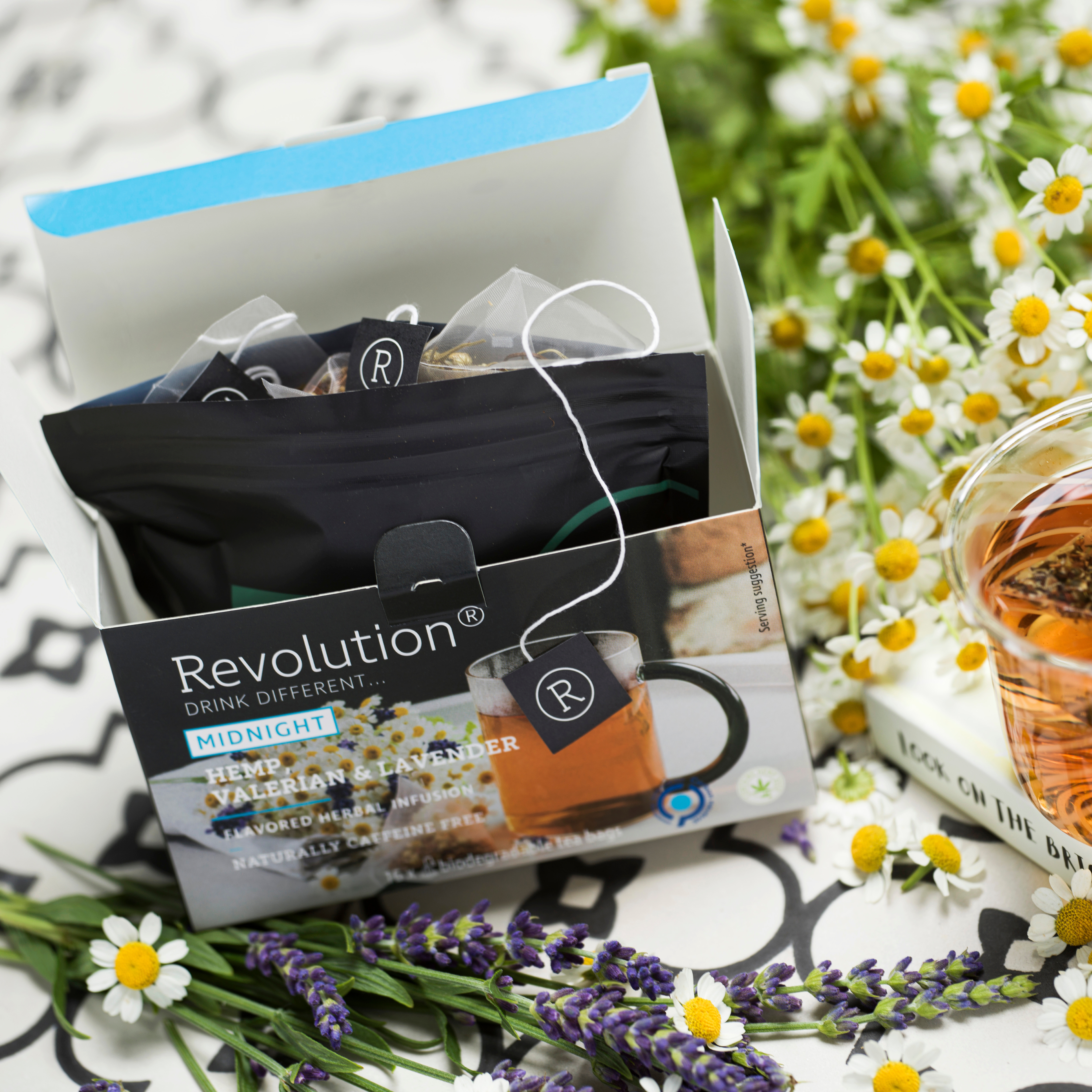 Open tea box with chamomile and lavender flowers, tea bags inside.