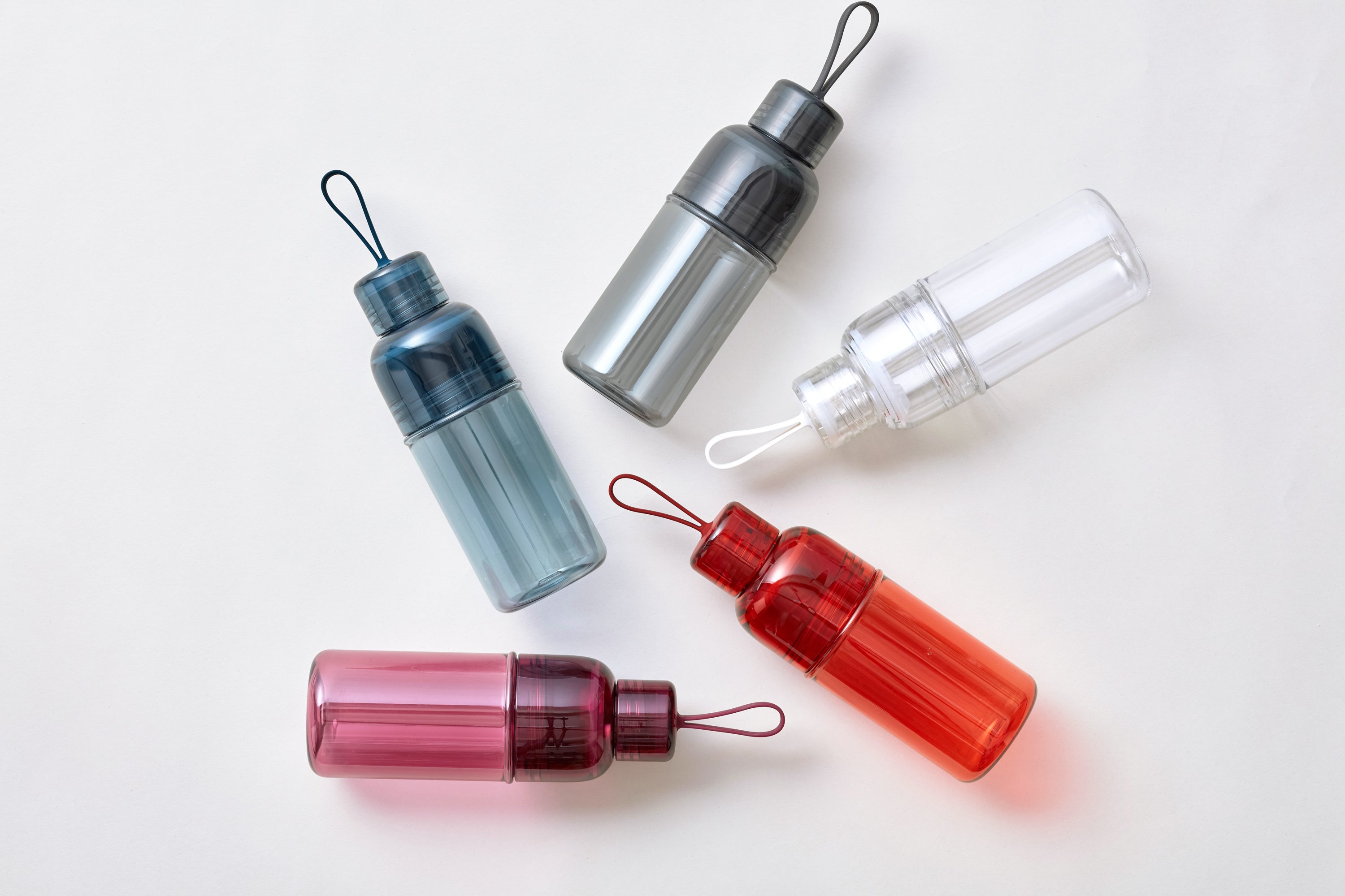 Five colorful plastic bottles arranged on a white surface.