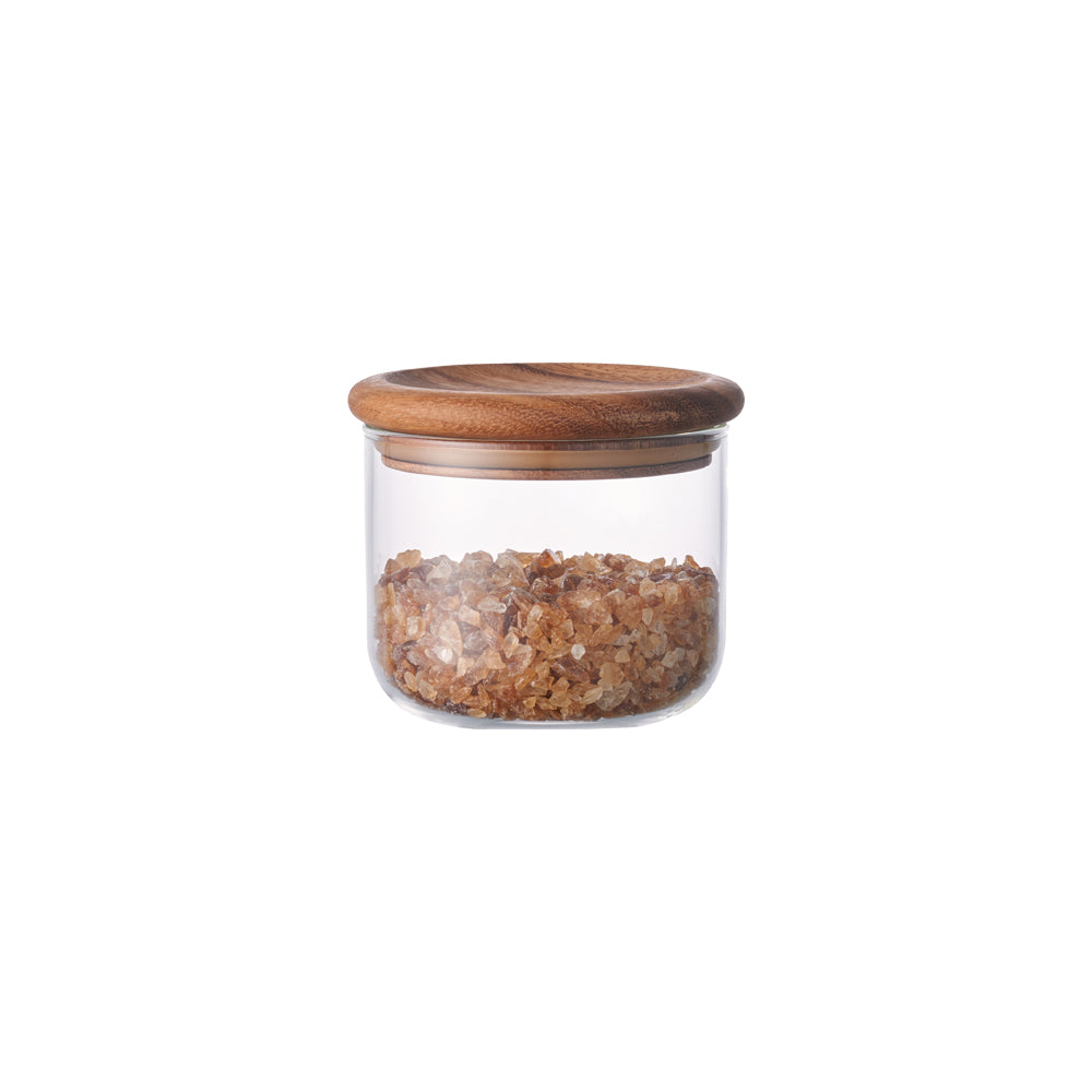 Clear glass jar with wooden lid, containing golden brown crystals.