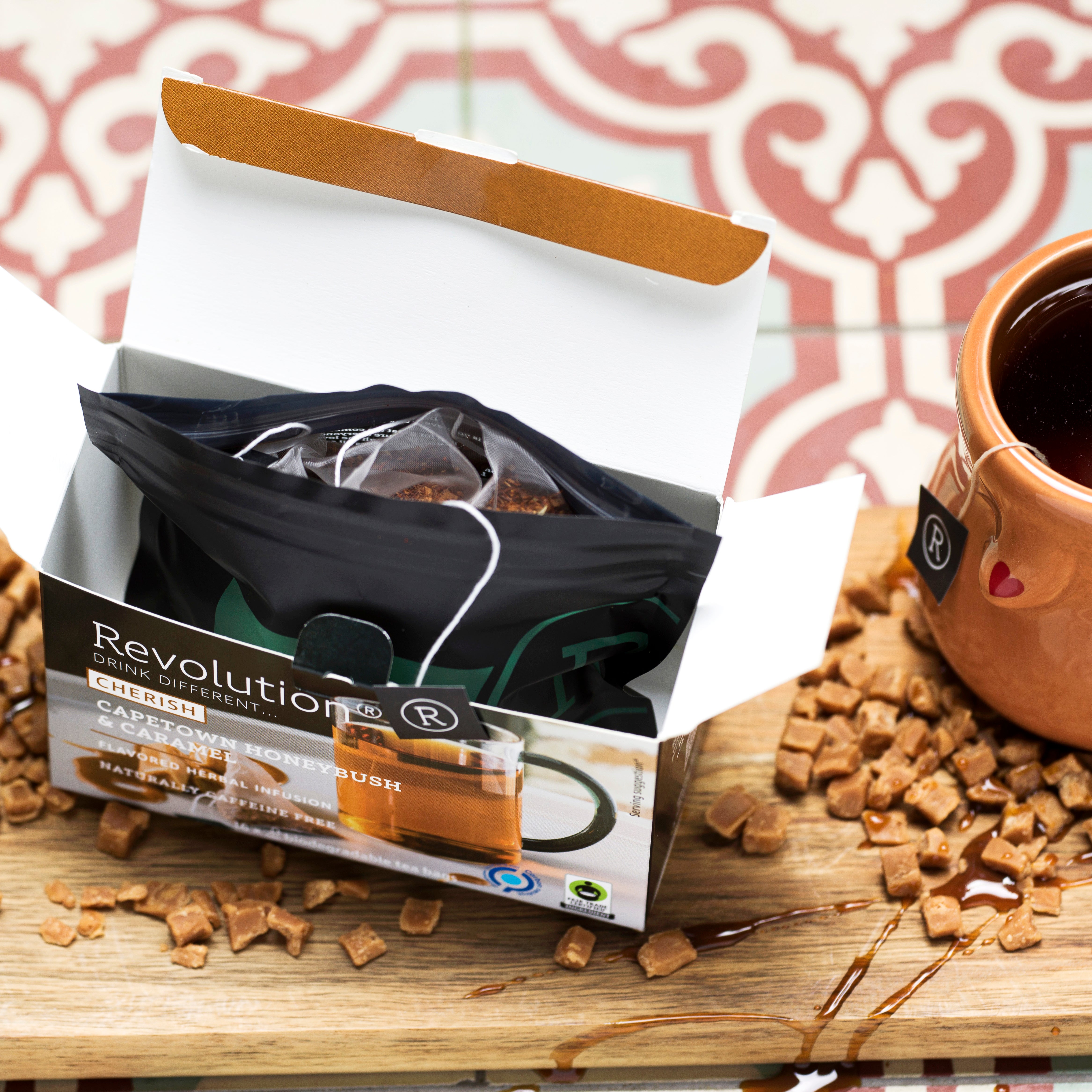 Open tea box, brown mug, and crumbly caramel pieces on a board.