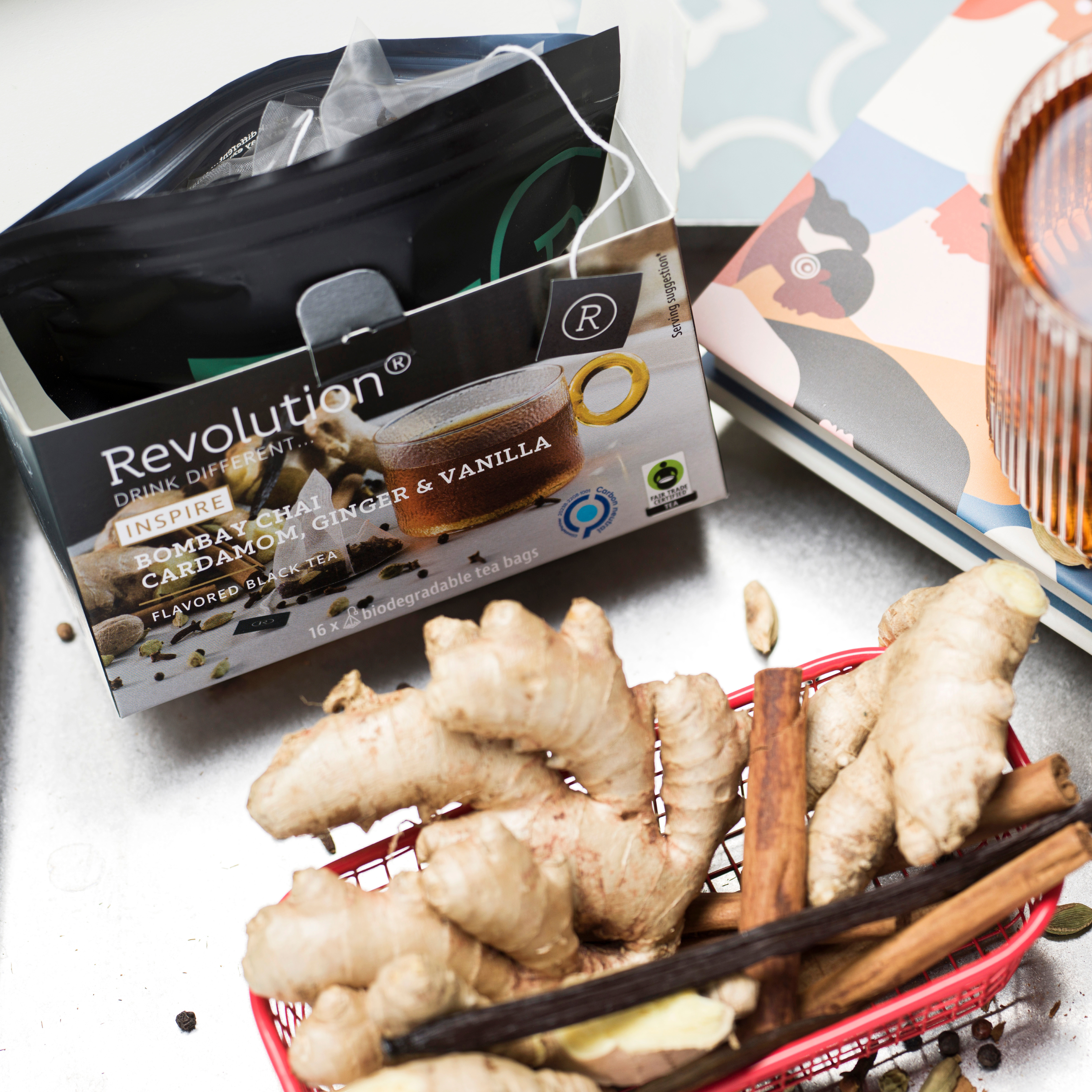 Tea box beside fresh ginger roots and a glass of amber liquid.