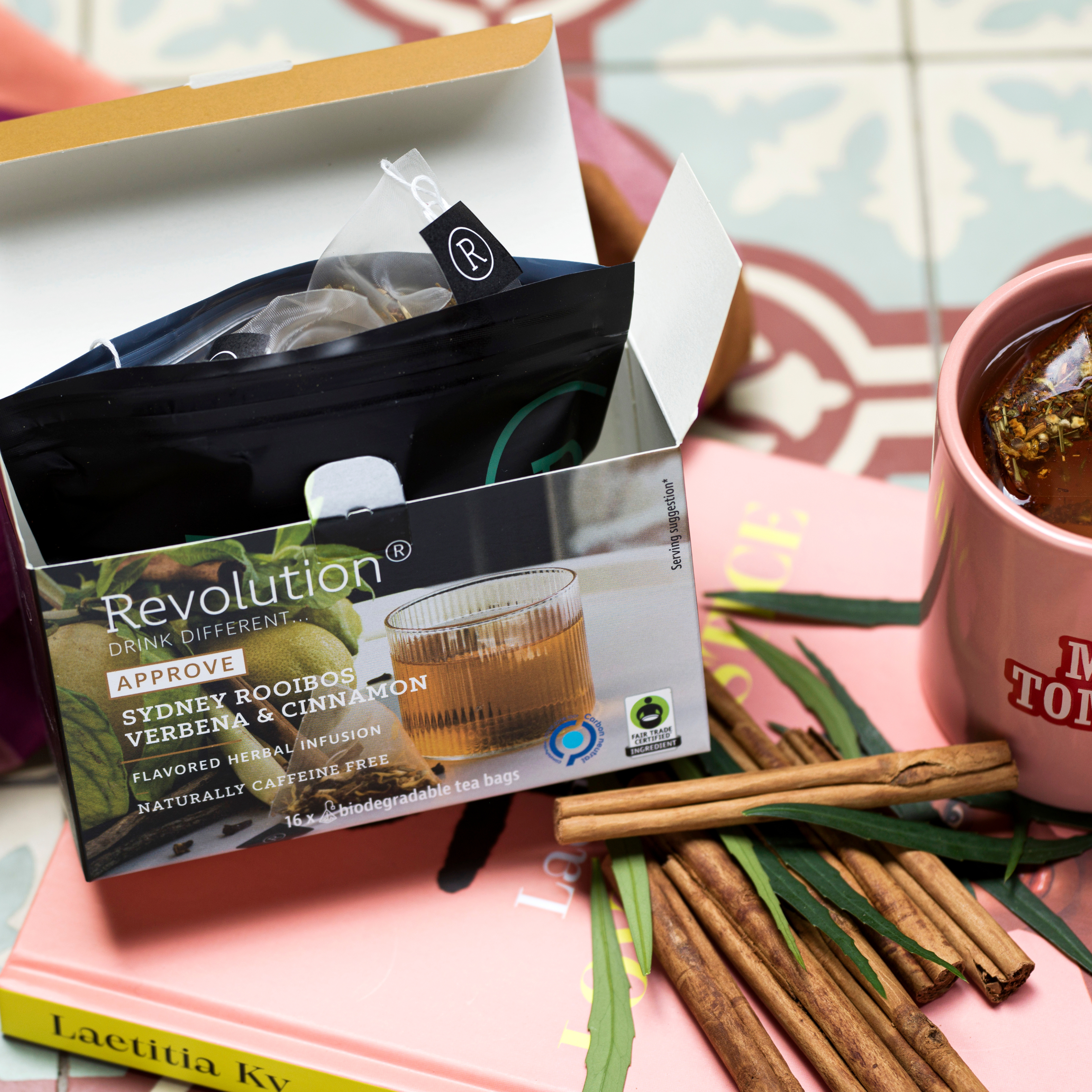 Tea box with cinnamon sticks, a book, and a pink mug.