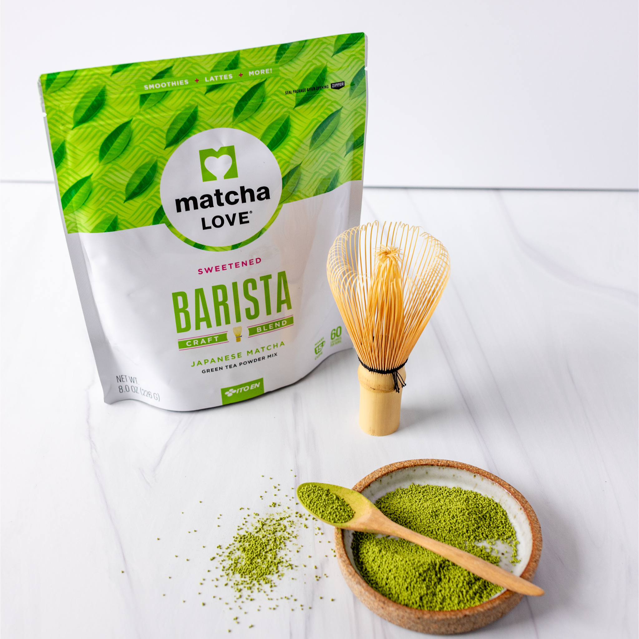 Matcha powder, bamboo whisk, spoon, and packet of matcha blend.